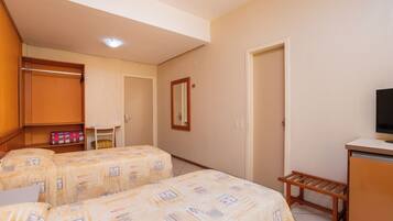 Habitación de hotel con dos camas, un armario, un escritorio y un televisor.