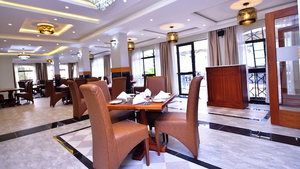 Une salle à manger d’hôtel avec de nombreuses tables et chaises, des lustres et de grandes fenêtres.