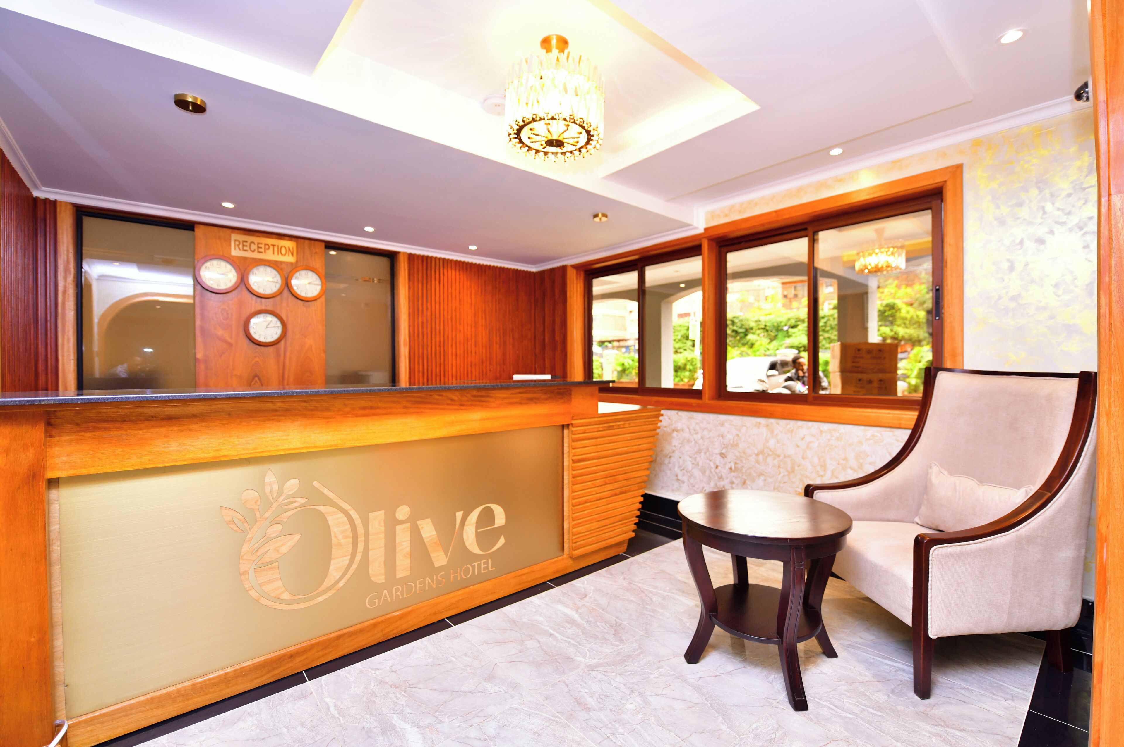 A reception area with a wooden reception desk, a chandelier, a sofa, and a view of the outdoors.