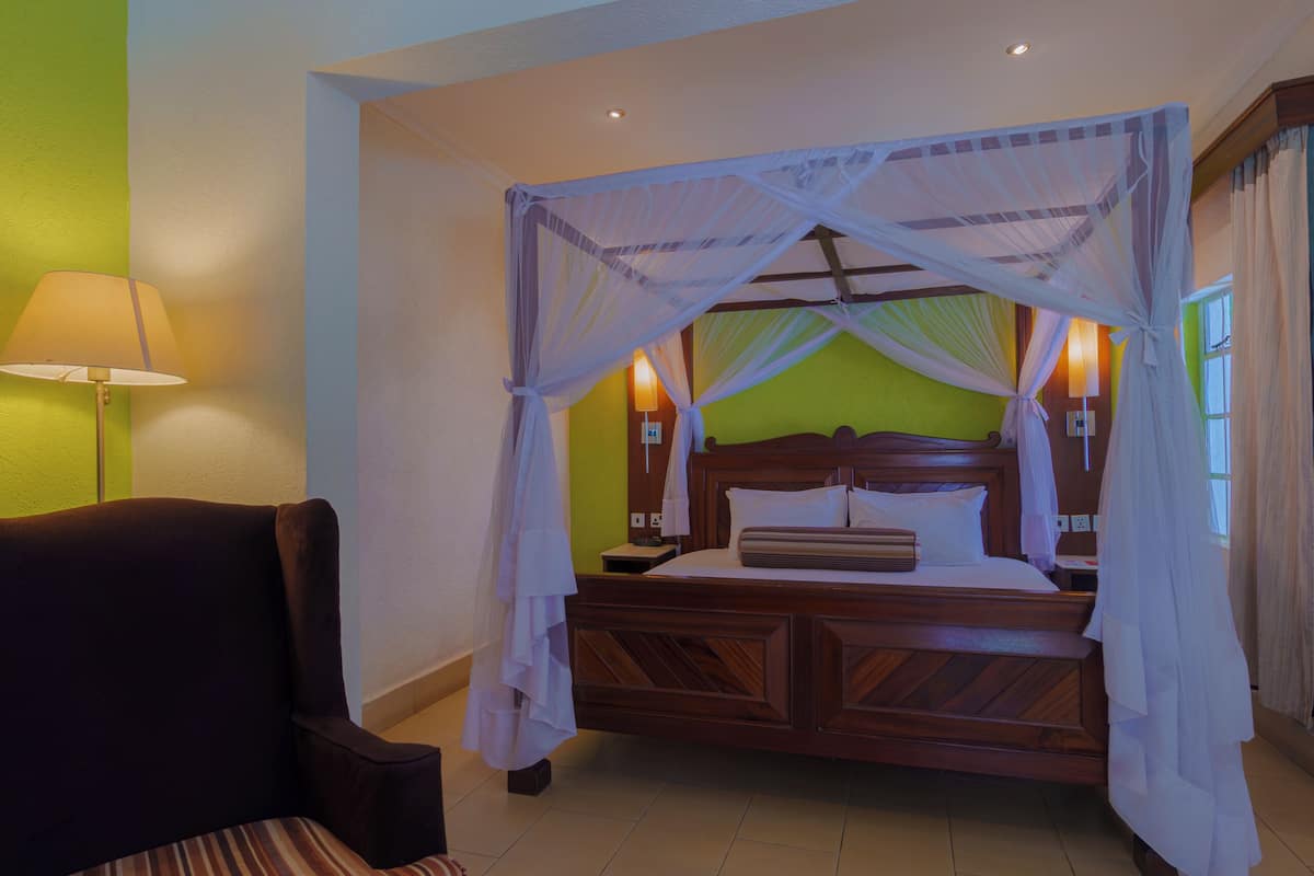 Ein Schlafzimmer mit Himmelbett, Nachttisch, Lampe und Stuhl.