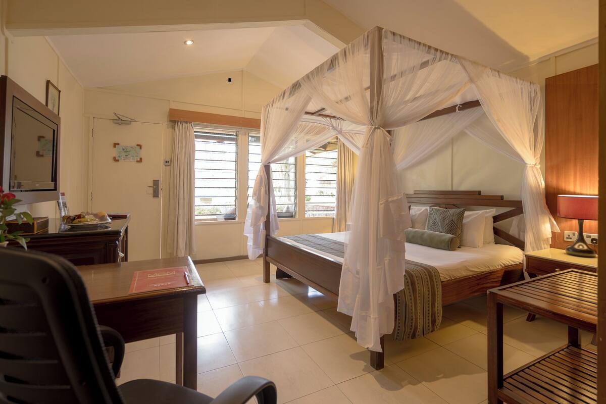 Ein Schlafzimmer mit Baldachinbett, Schreibtisch, Stuhl und Nachttisch.