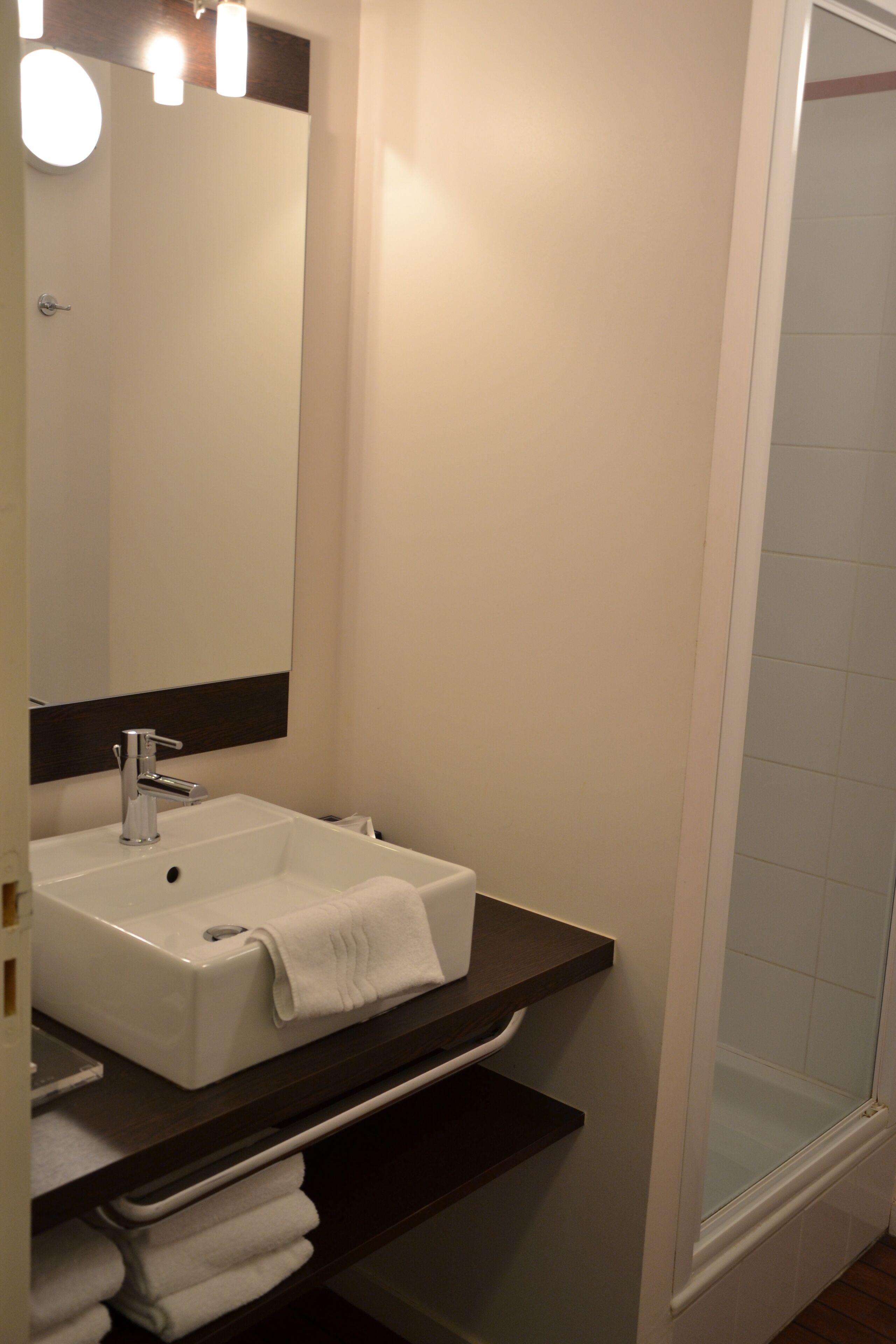 A bathroom with a white sink, a mirror, a towel rack, and a shower.