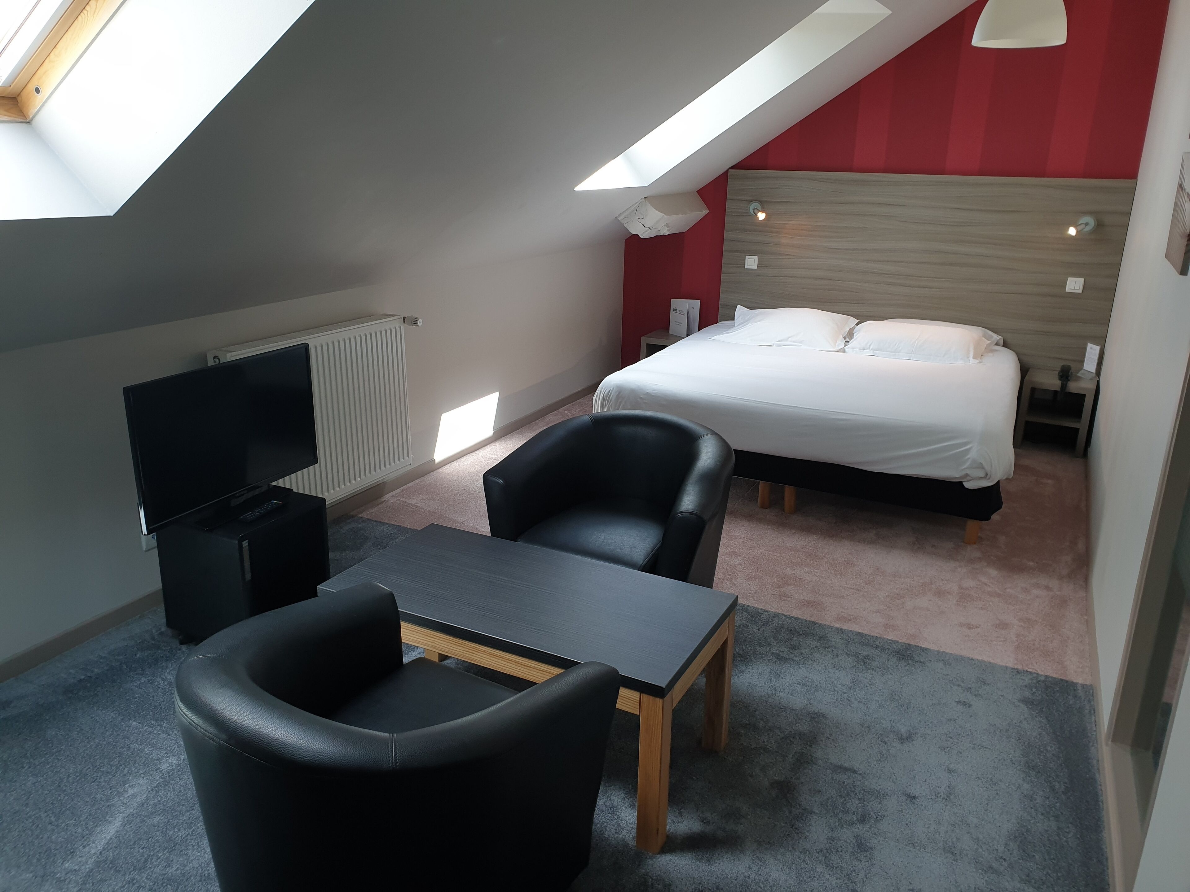 A hotel room with a bed, a TV, a desk, and a chair.