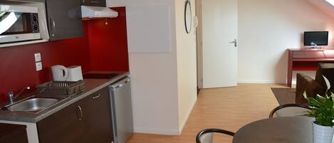Una cocina compacta con microondas, lavamanos y un pequeño comedor con mesa y sillas.