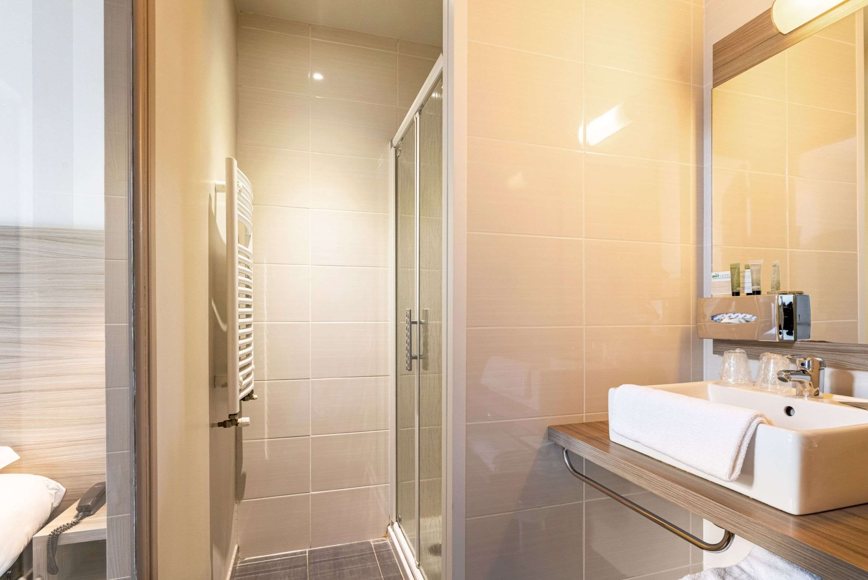 A modern bathroom with a glass shower enclosure, a white sink with a towel, and a mirror above the sink.