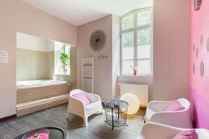 Habitación con bañera, dos sillas, una mesita, un radiador y una ventana con vistas.
