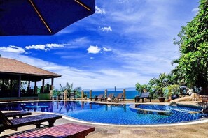 A pool area with lounge chairs and a covered seating area, overlooking a body of water. - Chaweng Bay View Resort (Koh Samui)