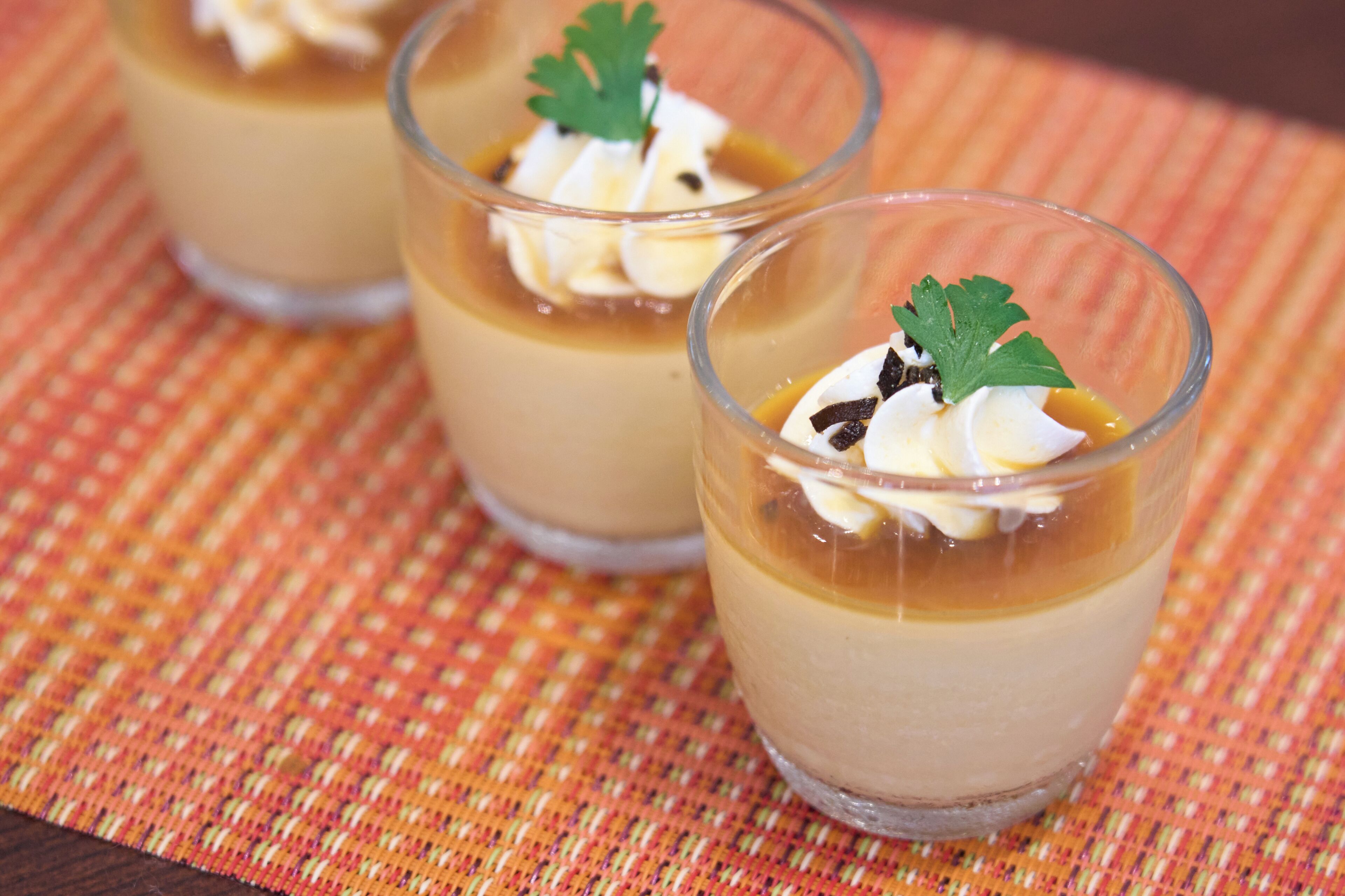 Three clear glasses of dessert with a garnish on a woven placemat.