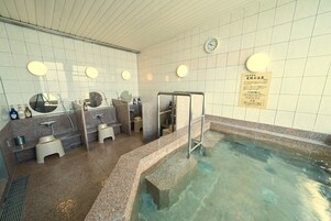 Un área de baños públicos con varios lavamanos, espejos y una piscina central.