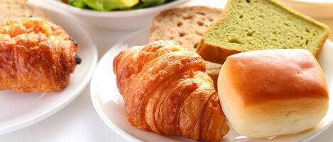 A plate with croissants, bread, and a sandwich.