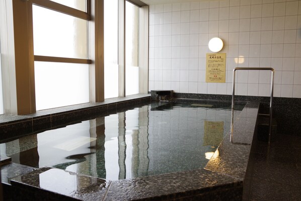 Una piscina amb aigua cristal·lina, una paret enrajolada i un senyal amb text.