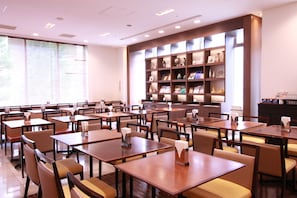 A restaurant with multiple tables and chairs, a large bookshelf with various items, and a window with blinds. - Hotel Hokke Club Osaka (Osaka)