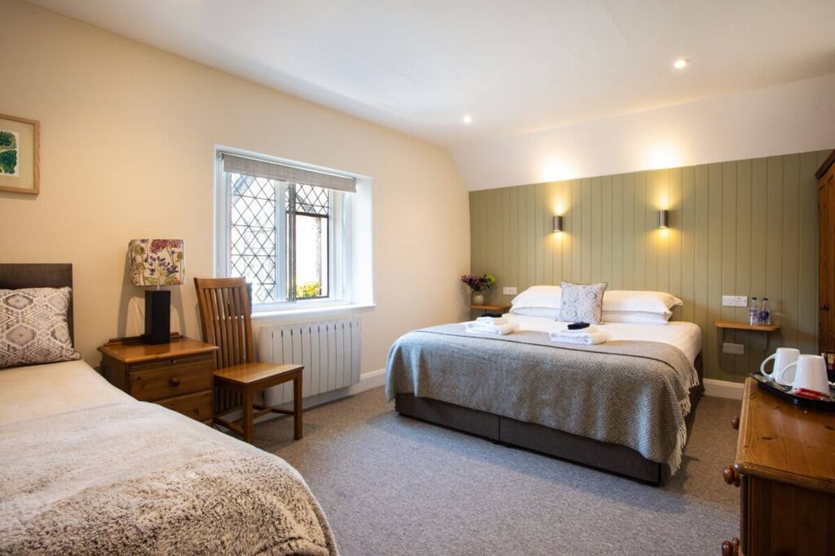 A bedroom with a large bed, a chair, a nightstand, a window, and wall-mounted lights.