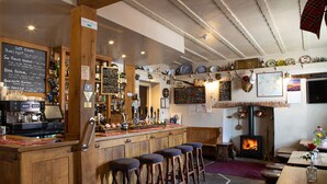 Una zona de bar con taburetes de madera, una máquina de café y una chimenea.