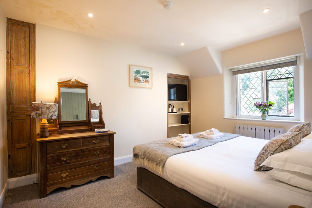A bedroom with a bed, dresser, mirror, and a window with a view.