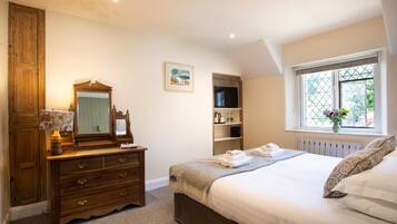 A bedroom with a bed, dresser, mirror, and a window with a view.