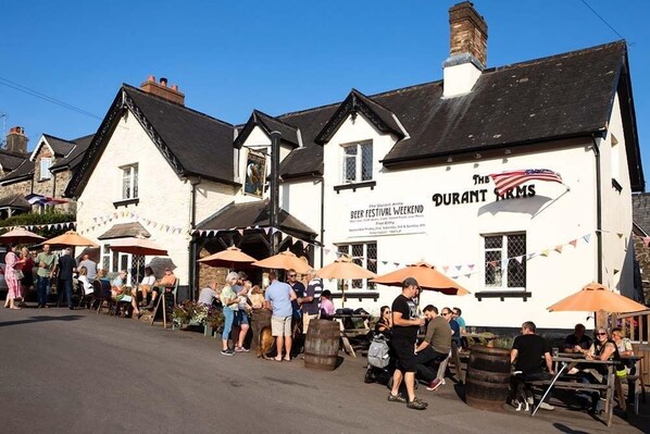 A white building with a sign for "The Durant Arms" and outdoor seating with umbrellas. - The Durant Arms (Totnes)