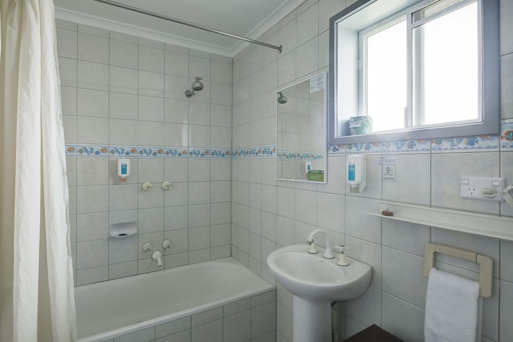 Un baño con bañera, lavamanos, ducha y ventana.