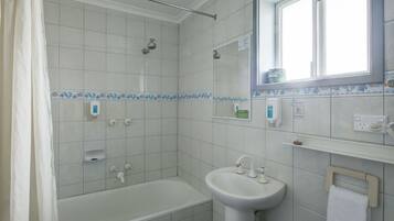 Un baño con bañera, lavamanos, ducha y ventana.