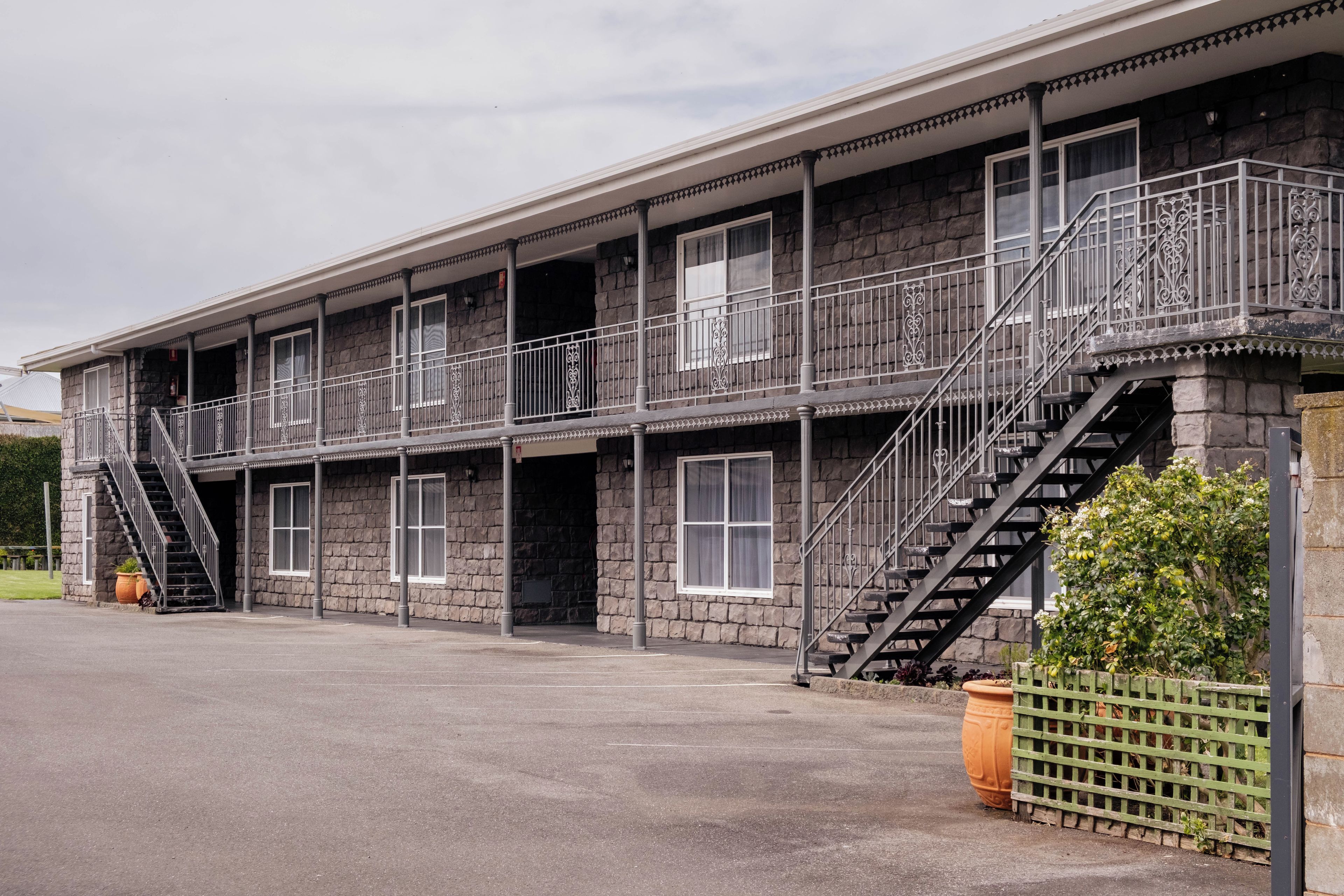 Un immeuble à plusieurs étages, doté d’une façade en pierre, de nombreux balcons avec des garde-corps en métal et d’une série d’escaliers menant aux étages supérieurs.