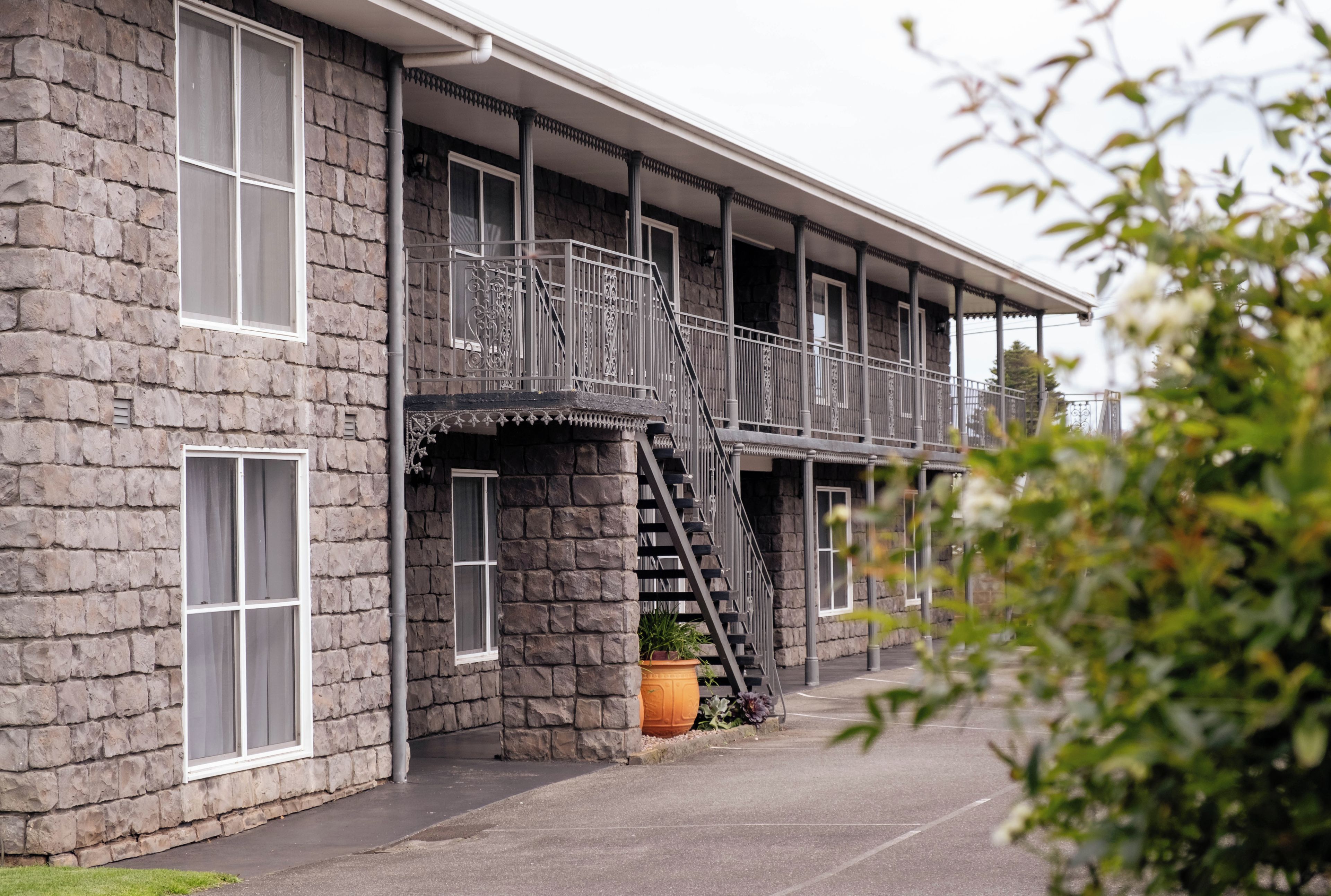 A two-story stone building with a balcony and a fire escape.