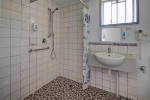 Bathroom features a shower, sink with mirror, and a window.