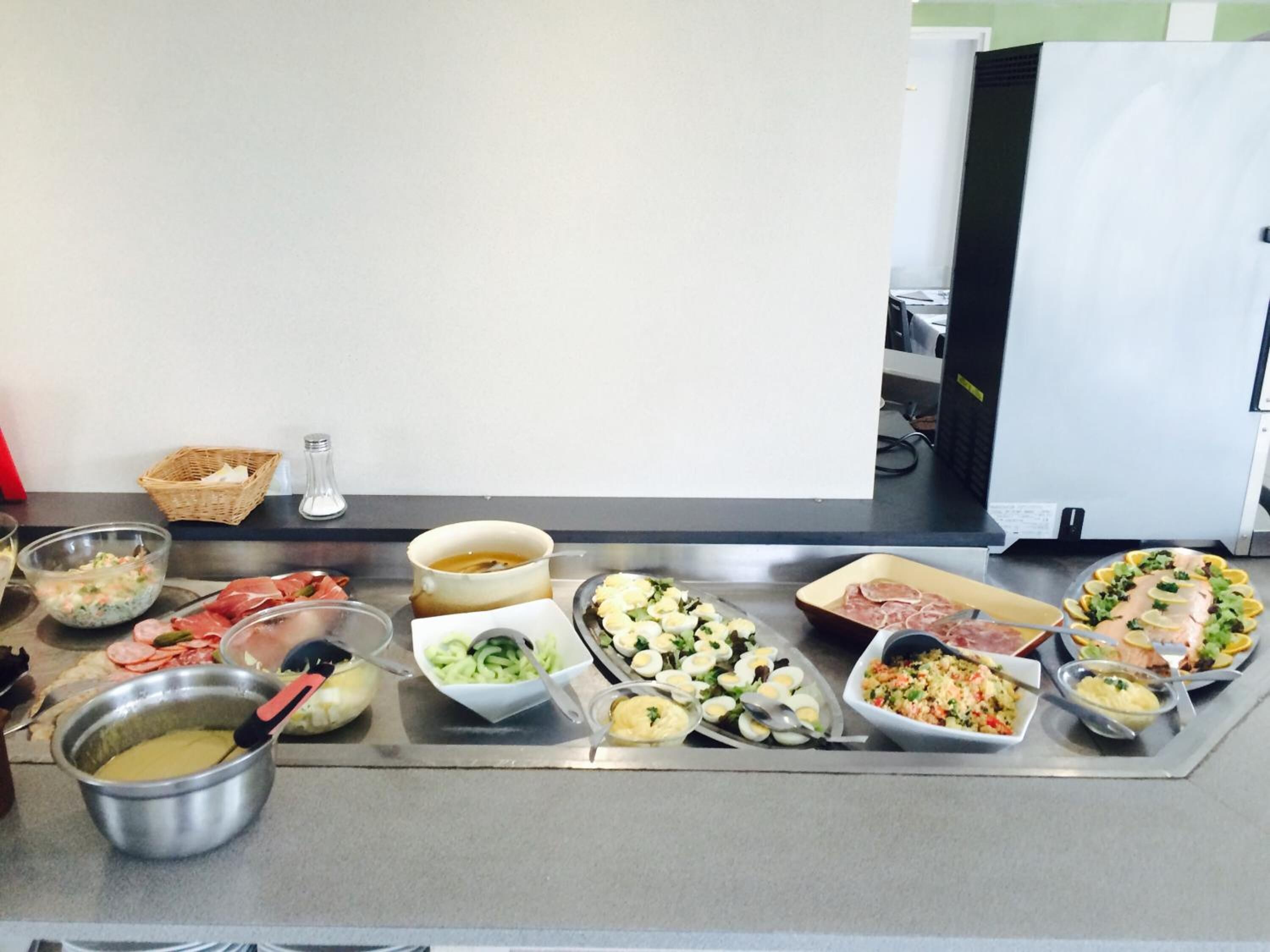 A buffet table with various food items including meats, salads, and a soup bowl.