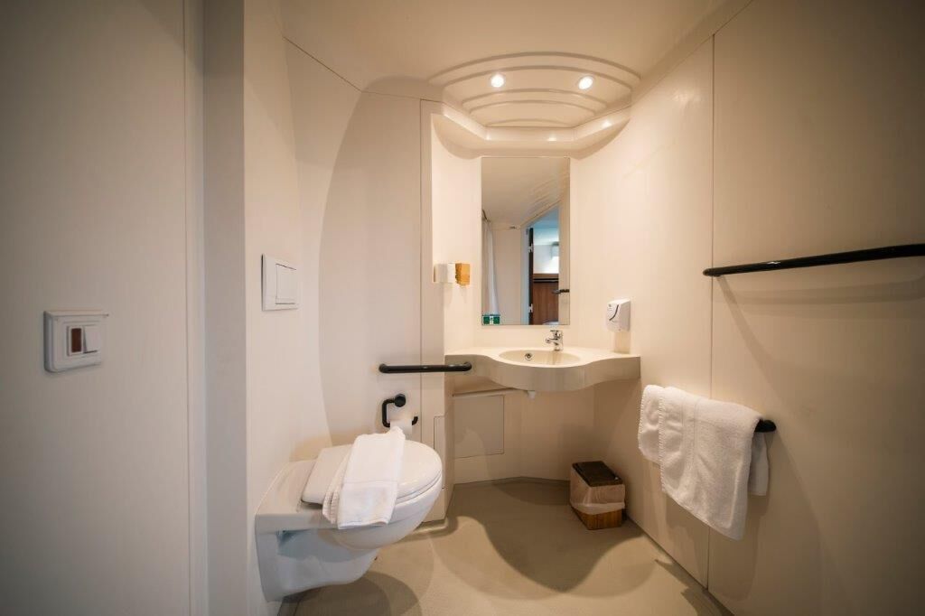 A modern bathroom with a toilet, sink, and mirror.