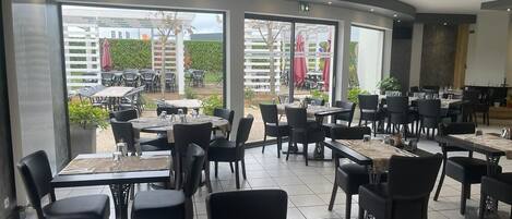 A restaurant with indoor and outdoor seating, large windows, and a modern design.