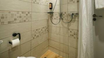 Un baño pequeño con azulejos, que incluye una ducha, un inodoro y un perchero para toallas.
