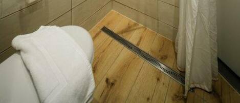 Un baño pequeño con azulejos, que incluye una ducha, un inodoro y un perchero para toallas.