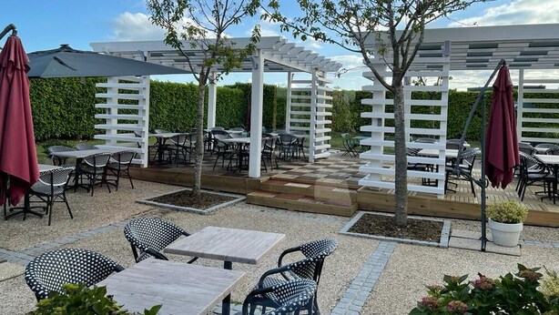Un patio al aire libre con pérgolas blancas, mesas y sillas.