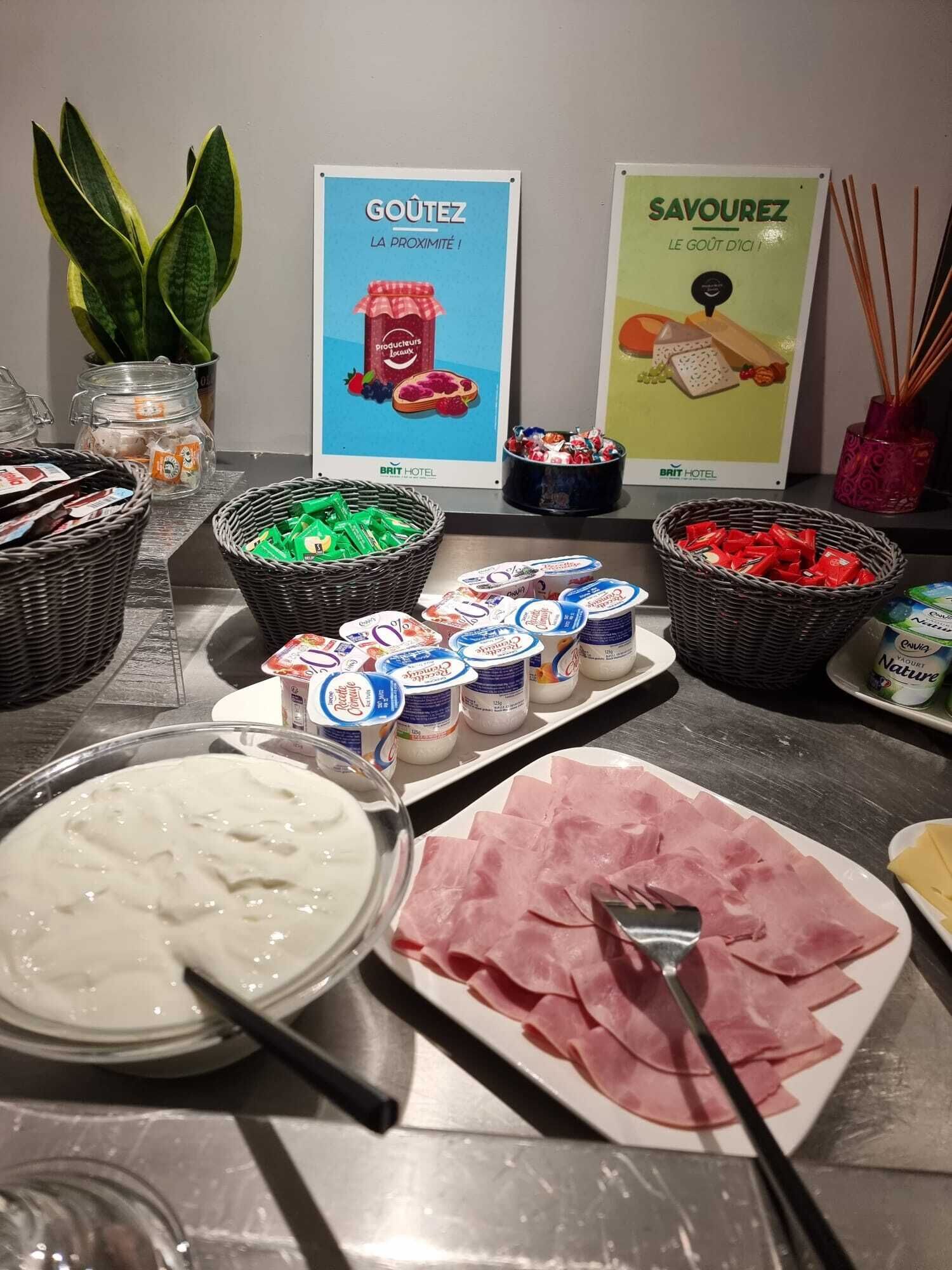 Ein reichhaltiges Buffet mit verschiedenen Speisen, darunter Joghurt, Schinken und Körben mit Snacks.