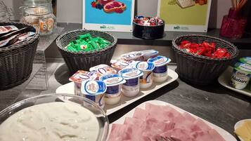 Ein reichhaltiges Buffet mit verschiedenen Speisen, darunter Joghurt, Schinken und Körben mit Snacks.