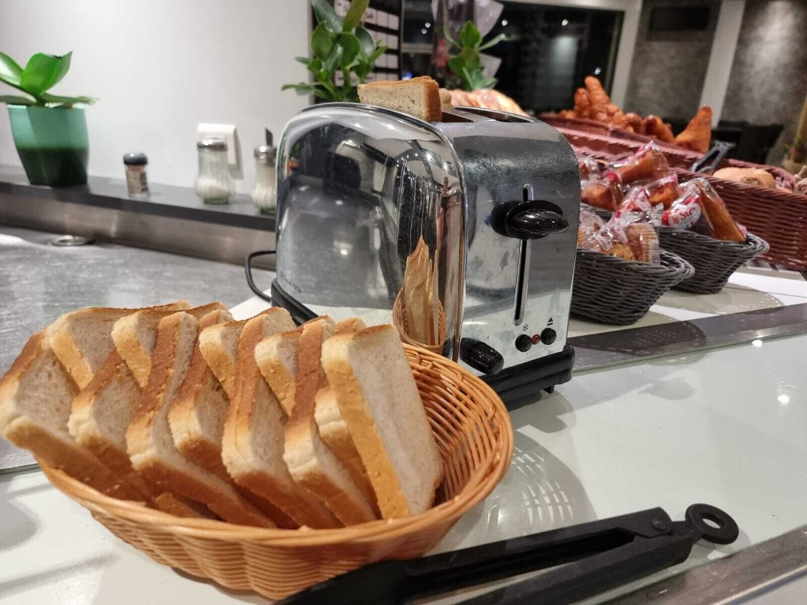 Un grille-pain avec un panier de tranches de pain devant.