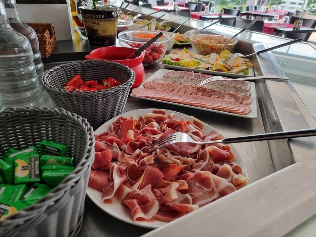 A buffet with various food items including sliced meats, salads, and beverages.