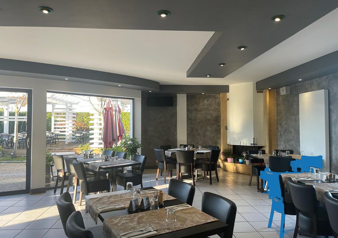 Un restaurante con mesas dentro y fuera, decoración moderna y vistas al exterior.