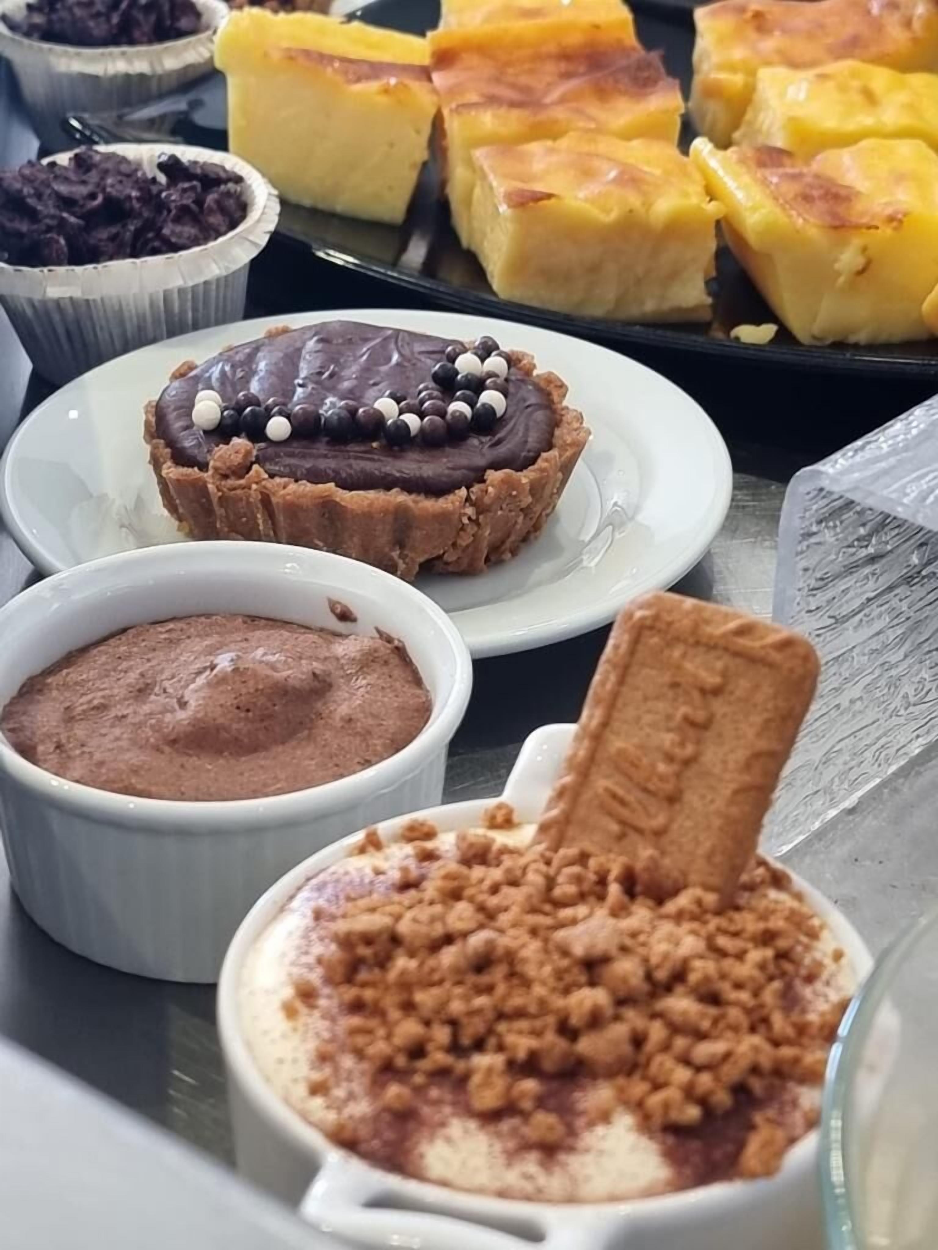 Un assortiment de desserts comprenant une tarte au chocolat, une crème pâtissière et un dessert aux fruits en crumble.