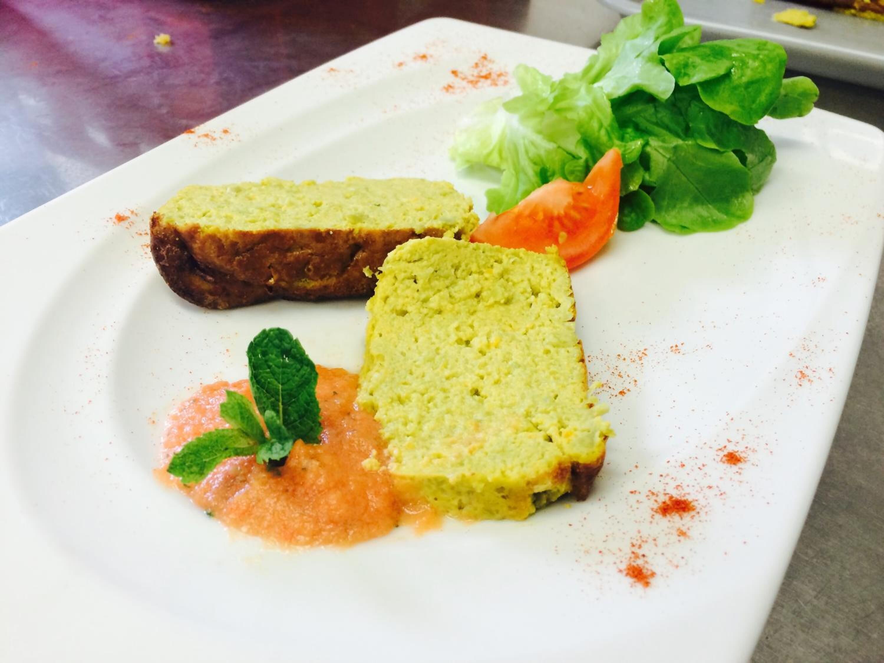 Un plato con dos rebanadas de pan, un tomate, lechuga y una ramita de menta.