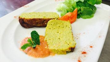 Un plato con dos rebanadas de pan, un tomate, lechuga y una ramita de menta.