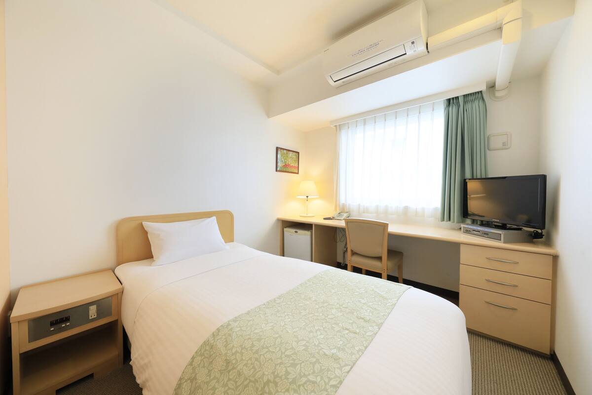 Une chambre d’hôtel équipée d’un lit, d’un bureau, d’une chaise, d’une télévision et d’un appareil de climatisation.