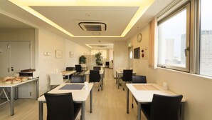 A modern dining area with tables and chairs, a clock on the wall, and a window with a city view. - Hotel Famy Inn Kinshicho (Tokyo)