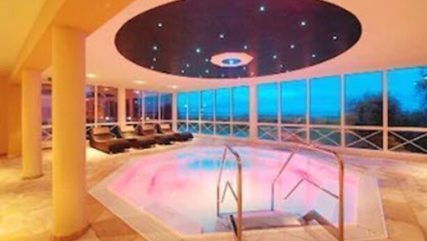 A large indoor swimming pool with a circular viewing area and a ceiling with a starry design. - Inselhof Vineta (Zempin)