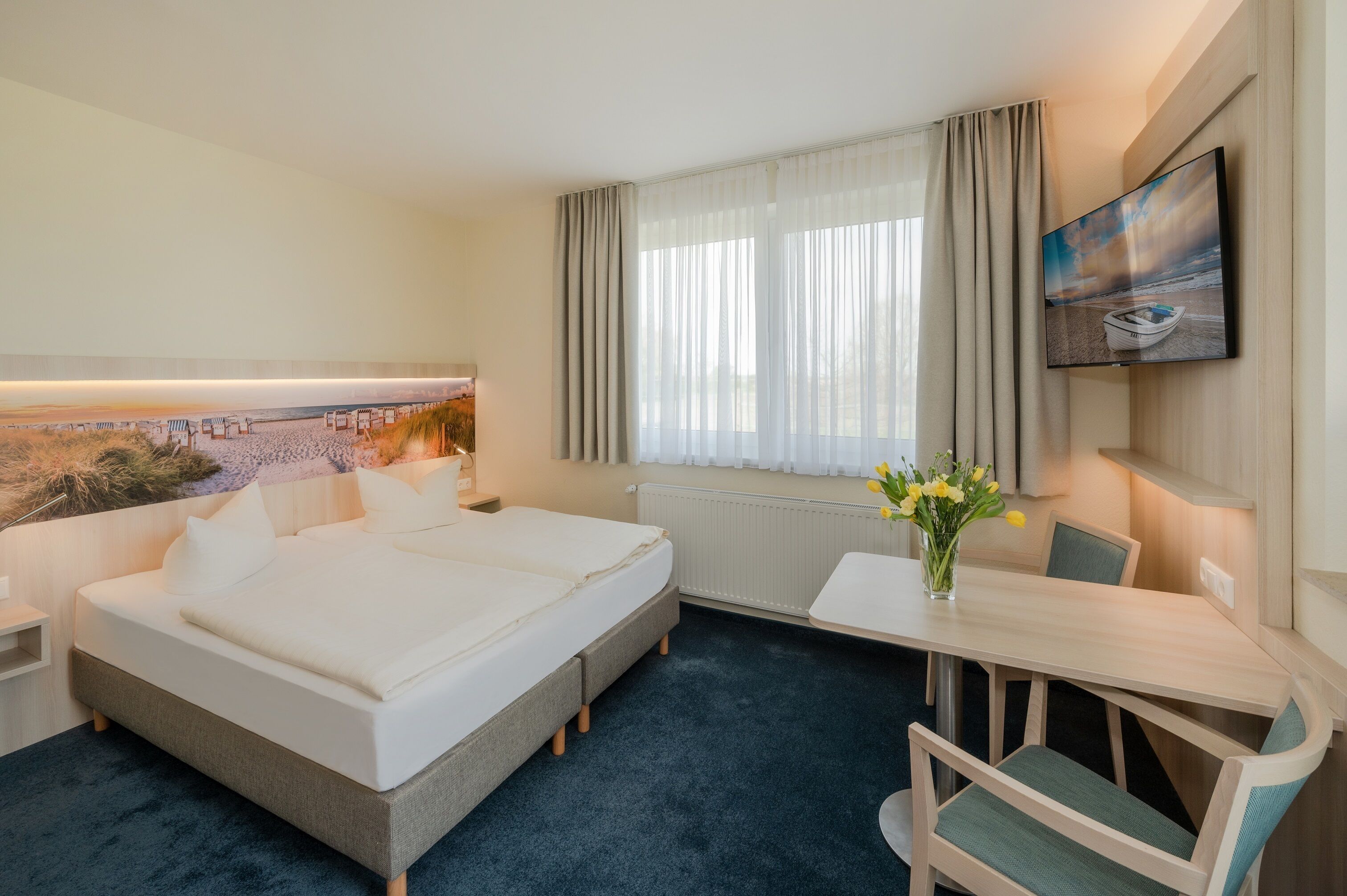 Una habitación de hotel con una cama grande, un escritorio, una silla, un televisor y una ventana con cortinas.