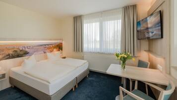 Una habitación de hotel con una cama grande, un escritorio, una silla, un televisor y una ventana con cortinas.