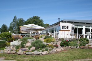Un bâtiment blanc de style « RV » (véhicule récréatif), portant le numéro 800 sur son côté, est entouré d’un jardin aménagé avec différentes plantes et rochers.