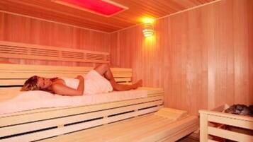 A sauna room with a wooden bench and a bed.