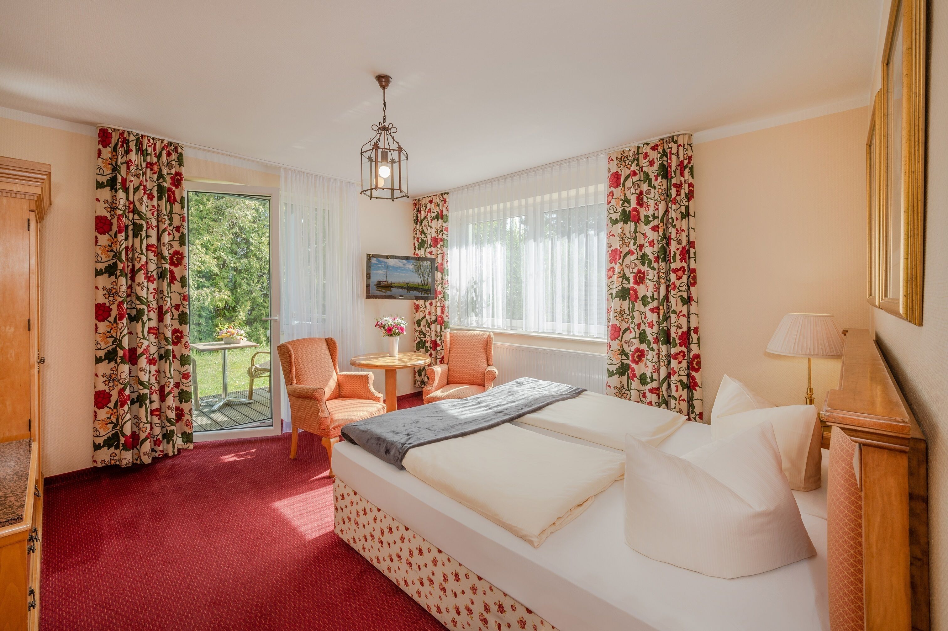 A hotel room with a bed, a desk, a chair, and a view of the outdoors.