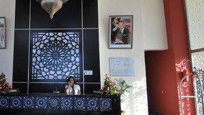 A reception desk with a decorative screen, framed photos, and potted plants. - Appart Hotel Founty Beach (Agadir)