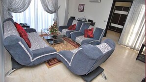 A living room with two grey sofas, a coffee table, and a small Christmas tree. - Appart Hotel Founty Beach (Agadir)